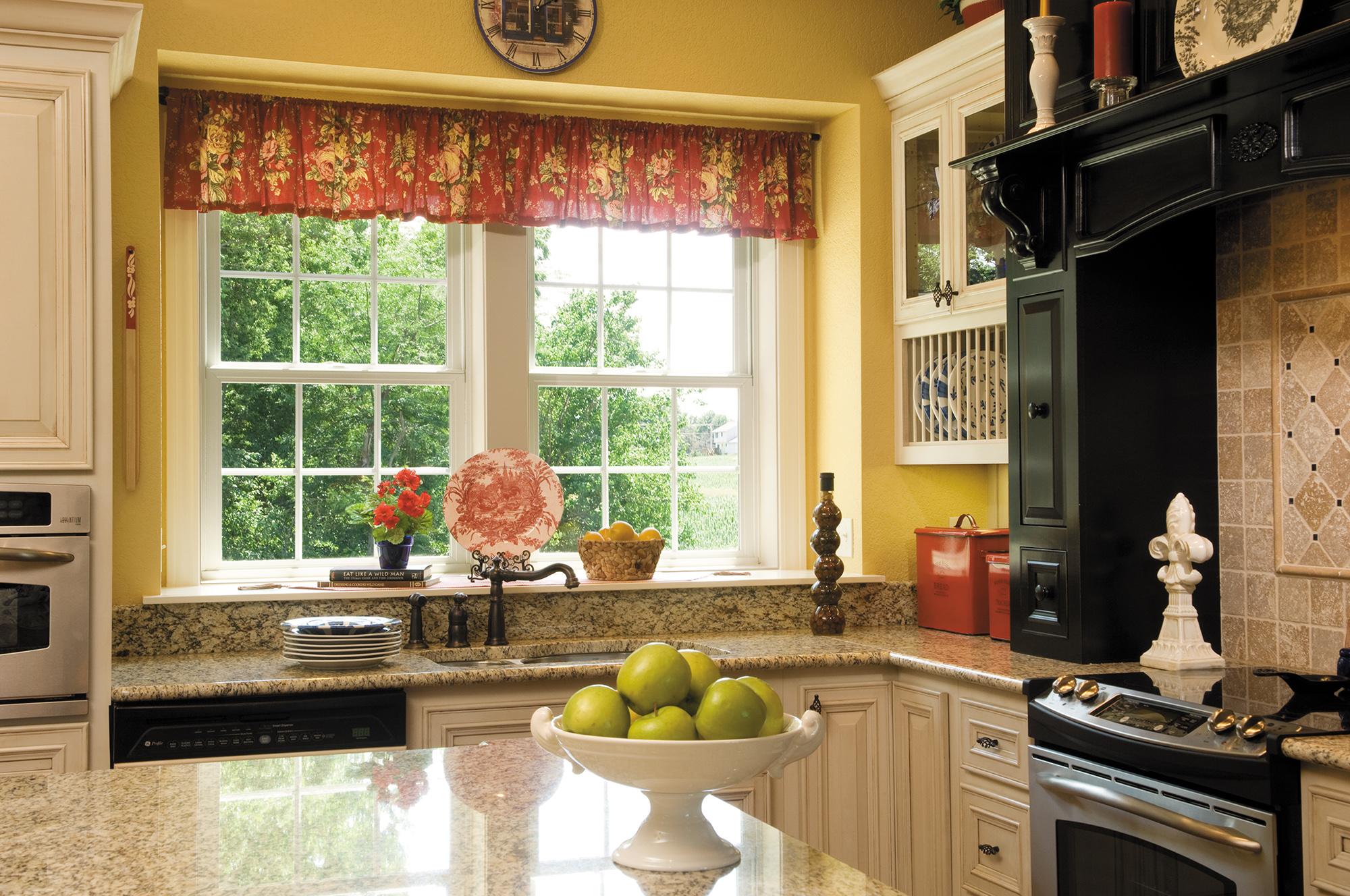 Wide kitchen windows overlooking a green landscape